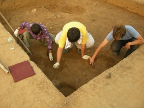 Robotnik, student archeologii z Pekinu oraz student archeologii z Polski przy doczyszczaniu stropu warstwy